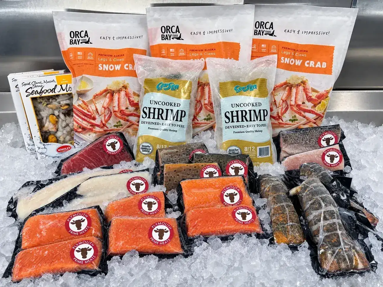 Fresh salmon, shrimp, snow crab and lobster tails displayed on ice